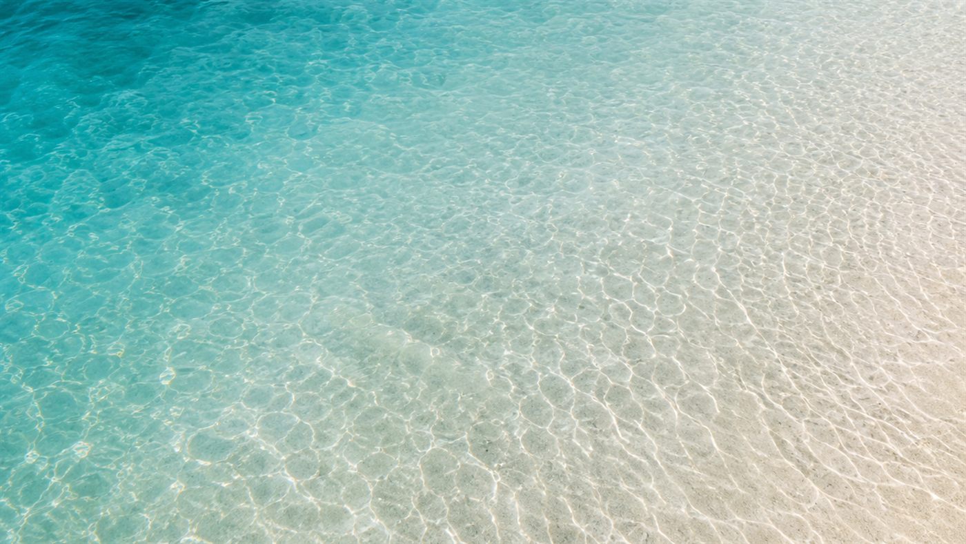 Sunlit turquoise shallows over pale rippled sand — the sea that gives Saelira its name