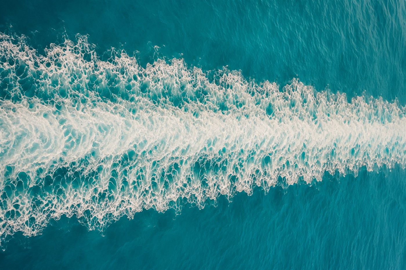 A ship's wake cutting a long white furrow across deep turquoise ocean, the literal meaning of Saelira